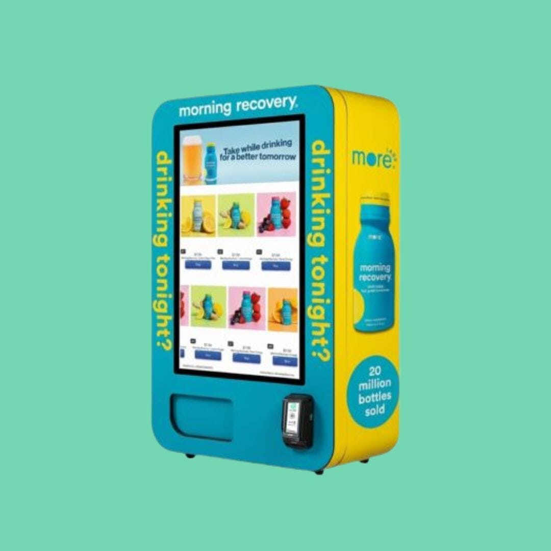 Morning Recovery slim wall vending machine with blue and yellow custom wrap, touchscreen product menu, and card reader.