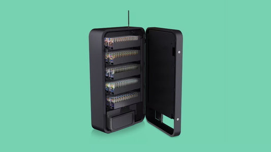 Wall-mounted Pokémon vending machine stocked with booster packs sealed in top loader cases.