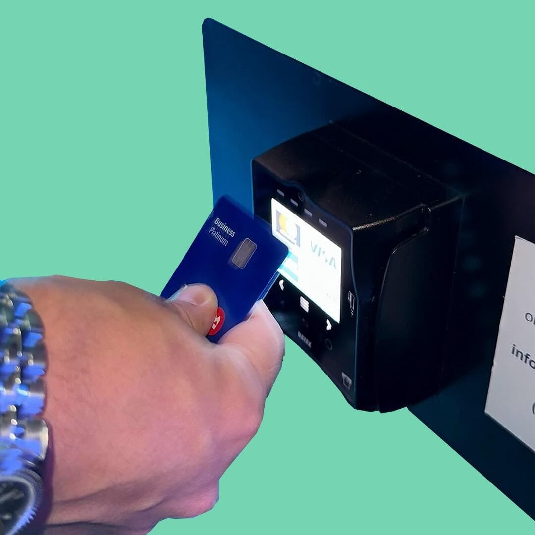 Customer holding a payment card in front of a NAYAX VPOS Touch device.